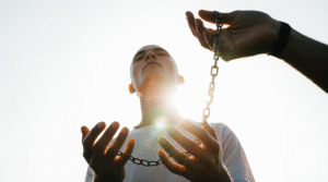 Quando a Fé se Torna uma Prisão Invisível Mãos soltam correntes na luz do sol, transmitindo sensação de libertação espiritual íntima