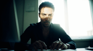 O Livre-Arbítrio Não É Soberano Pessoa adulta em escritório moderno pausando conscientemente com as mãos sobre teclado, expressão facial de reflexão ativa, iluminação natural realçando momento de decisão consciente